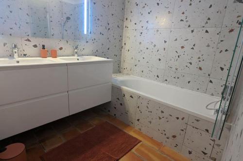 La salle de bains est pourvue d'un lavabo, d'une baignoire, d'un lavabo et d'un miroir. dans l'établissement Bas de villa avec piscine partagée, à Vallauris
