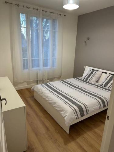 une chambre blanche avec un lit et une fenêtre dans l'établissement Modernité proche de Paris et du Stade de France, à Pierrefitte-sur-Seine
