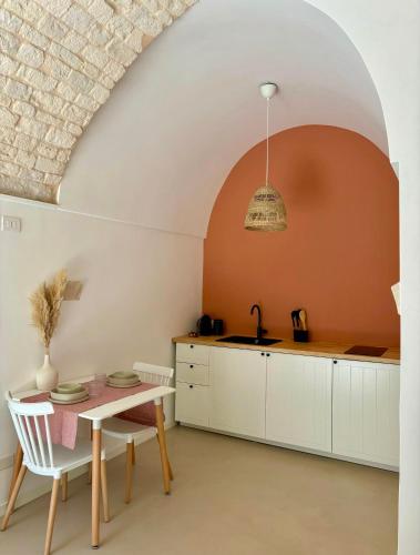 a kitchen with white cabinets and a table with a sink at Frida, suite in stile pugliese in Noci