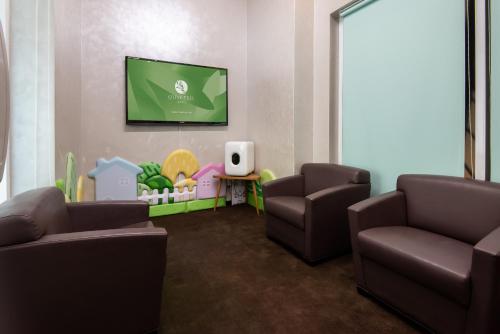a waiting room with two chairs and a flat screen tv at Olive Tree Hotel Penang in Bayan Lepas
