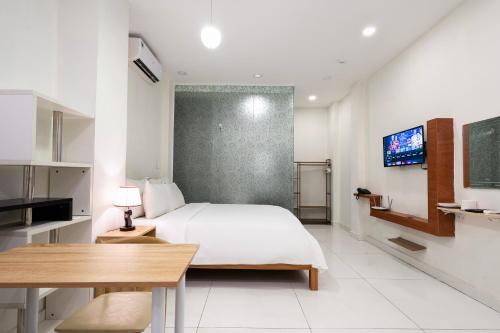 a bedroom with a bed and a table and a tv at Gemini Saigon CENTER - New & Quiet near Bui Vien Walking Street in Ho Chi Minh City