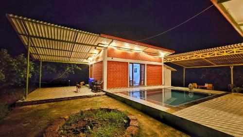 a house with a swimming pool at night at Farmhouse with Pool - Kalavady Farmstay in Baindūru