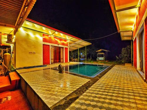 a house with a swimming pool at night at Farmhouse with Pool - Kalavady Farmstay in Baindūru