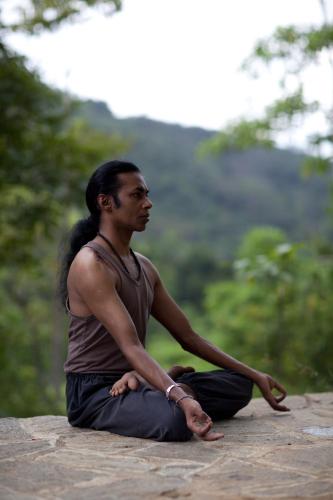 a man sitting on a rock doing a yoga pose at Royal Retreat ,Kandy in Kandy