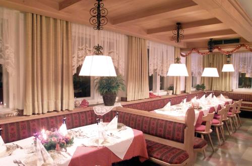 una sala da pranzo con tavoli, sedie e lampadari a braccio di Hotel Bruggerwirt a Anterselva di Mezzo