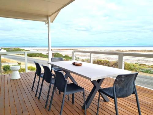 a table and chairs on a deck with the beach at Beachfront Beauty in Port Moonta