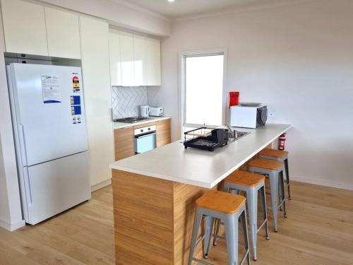 a kitchen with a white refrigerator and a counter with stools at Beachfront Beauty in Port Moonta
