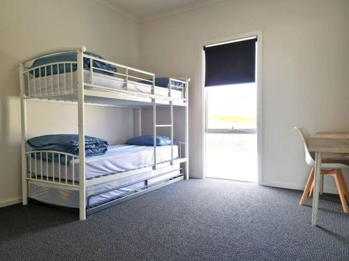 a bedroom with two bunk beds and a table at Beachfront Beauty in Port Moonta