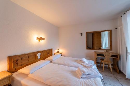 a bedroom with a large white bed with a wooden headboard at Chesa Silva - Silvaplana in Silvaplana