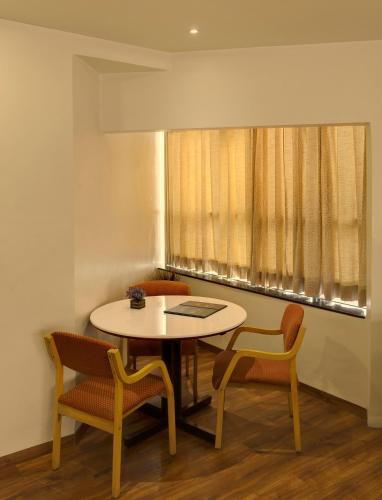 a room with a table and chairs and a window at Hotel Orient Crown, Kolhapur in Kolhapur