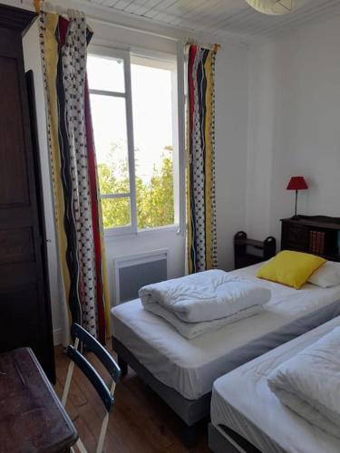 deux lits dans une chambre avec une fenêtre dans l'établissement Les Chouans, à Noirmoutier-en-l'lle