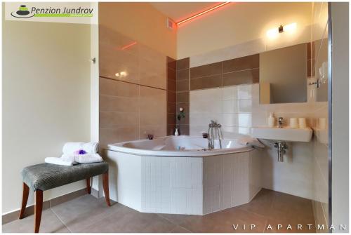 a bathroom with a tub and a chair and a sink at Penzion Vanessa in Brno