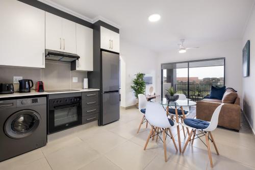 a kitchen and living room with a table and chairs at Ballito Village Luxury Apartments in Ballito