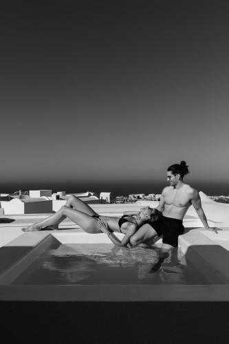 two men and a woman sitting in a swimming pool at Neo Suites in Fira