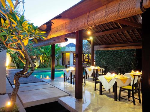 a restaurant with tables and chairs and a pool at The Amala Boutique Retreat in Seminyak