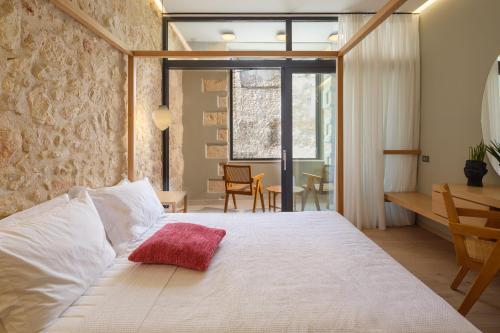 a bedroom with a large bed with a red pillow on it at The Alma City Hotel in Chania Town