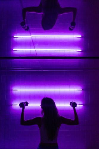 a woman standing in front of a wall with purple lights at Neo Suites in Fira