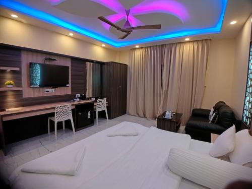 a hotel room with a bed and a desk and a tv at The Triton Beach Resort in Mandarmoni