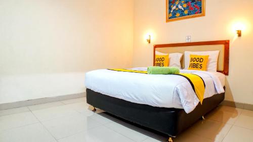 a bedroom with a large bed with yellow and white pillows at Hotel Horton by My Hospitality in Cirebon