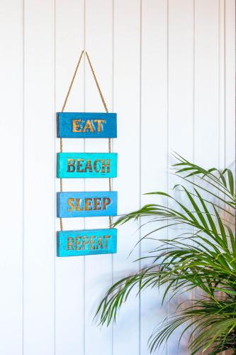a street sign that reads eat beach sleep repeat at Peak's Cabin - Endless Ocean Views - Fireplace - Fast WiFi in Wilderness