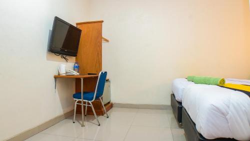 a room with a bed and a desk and a television at Hotel Horton by My Hospitality in Cirebon
