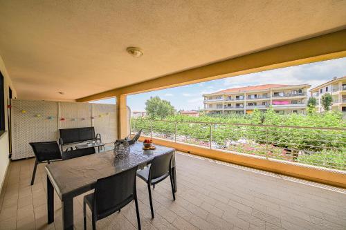 un balcon avec une table et des chaises et une grande fenêtre dans l'établissement Résidence costa d'oro HYPER CENTRE DE FOLELLI, à Folelli