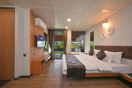 ein Schlafzimmer mit einem großen Bett und einem Fernseher in der Unterkunft Bliss Nirvana Resort, Lonavala in Lonavla