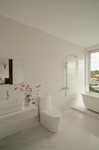 a white bathroom with two sinks and a toilet at The Manor Villas Da Lat in Xuan An