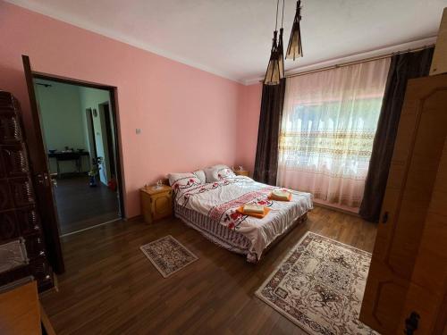 a pink bedroom with a bed and a window at Casa- viata la tara in Bucureşci