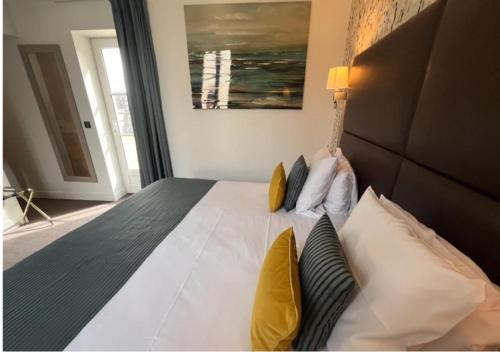 a bedroom with a large white bed with yellow pillows at La Maison de Mathilde in Bayeux