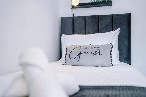 a bed with a white pillow with the words be our guest at Modern Premium 3 Bed Hidden Gem - Central Location in Barnsley