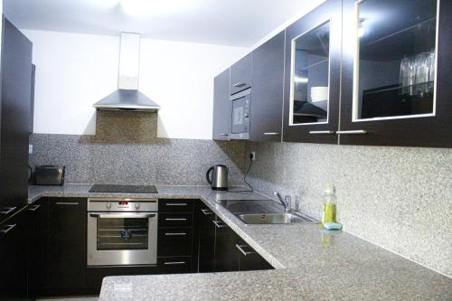 a kitchen with black cabinets and a sink at Wateera Jebel Sifah in As Sīfah