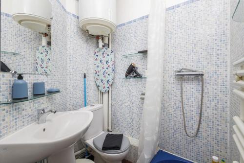 a blue tiled bathroom with a toilet and a sink at ANJ Appartement Centre Ville in Deauville