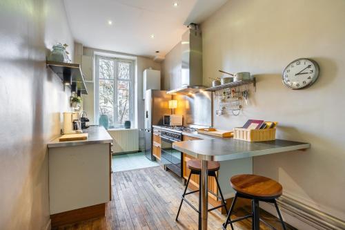 une cuisine avec une table et une horloge au mur dans l'établissement Le Chic d'Adam - À côté du parc de la Pépinière, à Nancy