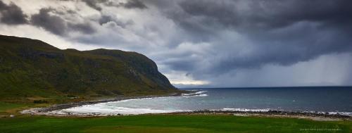 a storm looming over the ocean with a beach at Alnes Gård in Ålesund