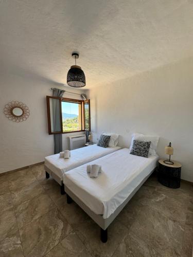 une chambre avec deux lits et une fenêtre dans l'établissement Appartement à 2 pas de la plage, à Olmeto