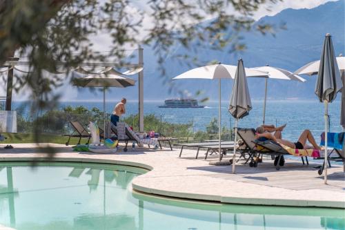 a group of people laying in chairs by a swimming pool at Ambienthotel PrimaLuna 3S in Malcesine