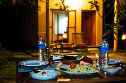 a table with plates of food and bottles of water at River paradise safari house with cooking class in Udawalawe