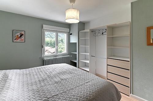ein Schlafzimmer mit einem Bett, einem Fenster und Regalen in der Unterkunft Le Cocoon Clairefontaine - Maison vue montagne in Cornimont