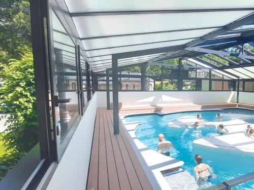 un groupe de personnes nageant dans une piscine dans l'établissement Grand Hôtel de Bourbon-Lancy - Spa et Restaurant - Logis, à Bourbon-Lancy