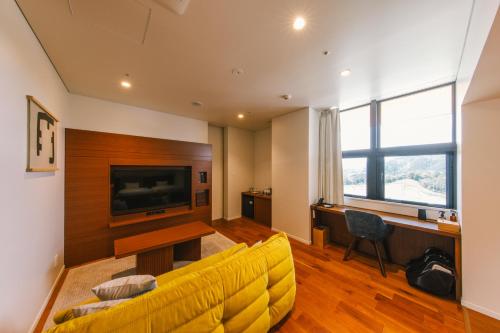 a living room with a yellow couch and a television at Hotel Vison in Taki