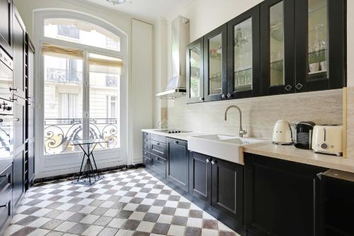 une cuisine avec des armoires noires et un sol en damier dans l'établissement Sublime apartment - 2BR-4P - Arc de Triomphe, à Paris