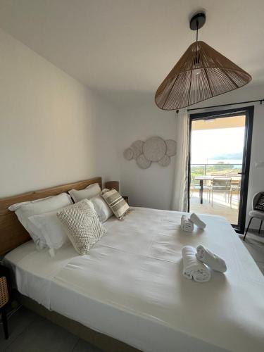 une chambre avec un grand lit blanc avec des serviettes dessus dans l'établissement T3 de standing neuf vue mer, à Propriano