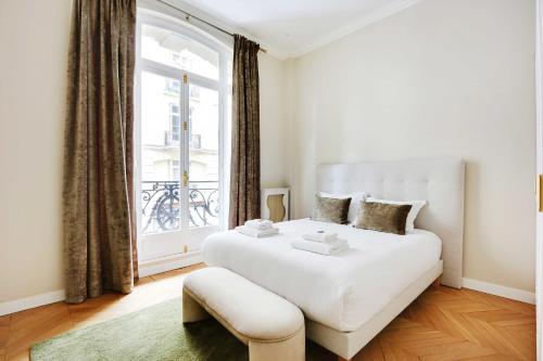 une chambre avec un grand lit blanc et une fenêtre dans l'établissement Sublime apartment - 2BR-4P - Arc de Triomphe, à Paris