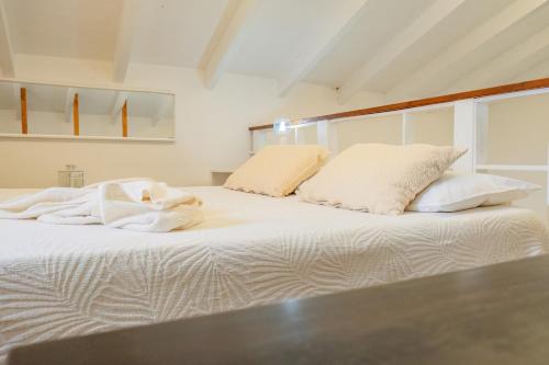 a white bed with white sheets and pillows on it at HISTORIA- Dimore Vico Ghezzi in Carpignano Salentino