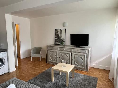 un salon avec une télévision et une table dans l'établissement Harmonie - Affaires & Loisirs à Rueil, à Rueil-Malmaison