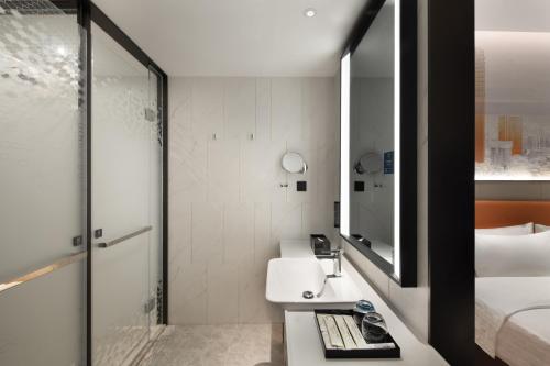 a bathroom with a sink and a bed and a mirror at 东莞大朗希尔顿欢朋酒店 in Huangcaolang