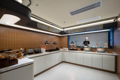 a kitchen with a person standing in the kitchen at Atour Hotel Qidong Wenfeng World People's West Road in Qidong