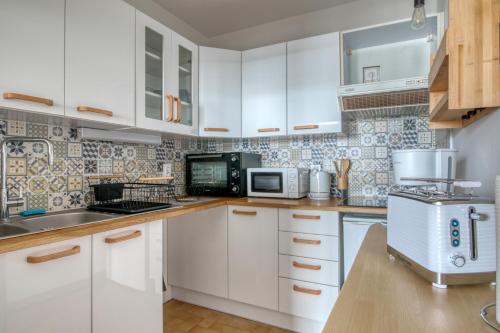 une cuisine avec des armoires blanches et un micro-ondes dans l'établissement Le Cocon de Port-Louis - Appt à 200m de la plage, à Port-Louis