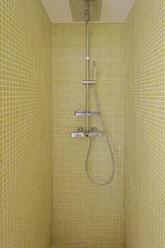 a bathroom with a shower in a yellow tiled wall at Villa Aya Barca in Santa Susanna